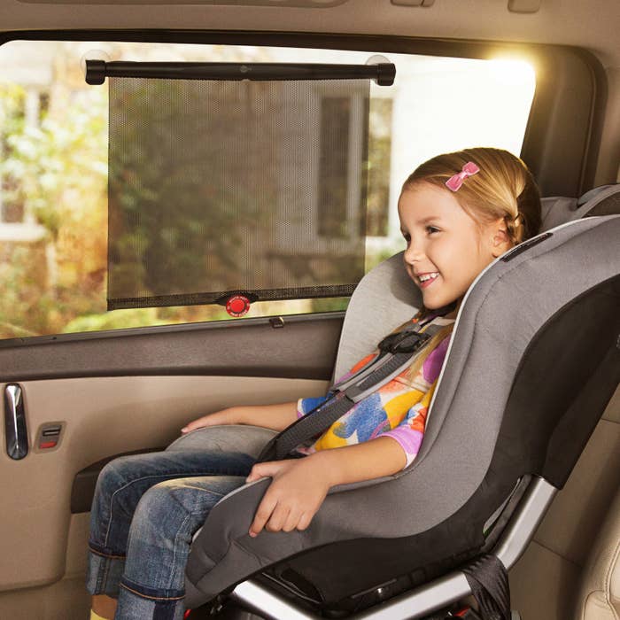 child in a car seat with a sun shade blocking the sun on the window