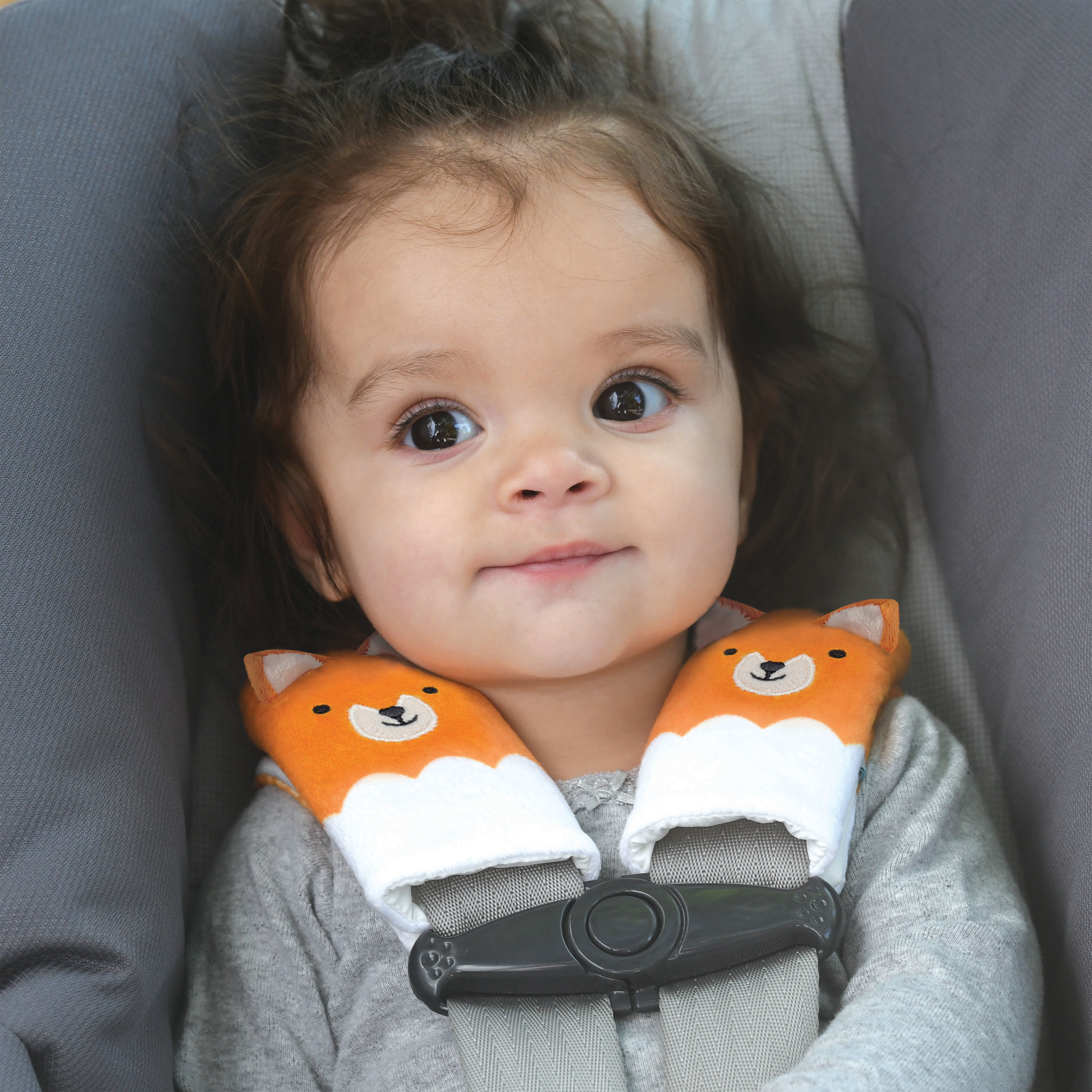 child in a car seat with fox-shaped strap covers on the car seat straps