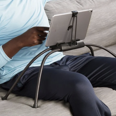 A model using the four legged flexible black stand on a couch with their tablet hovering above their lap