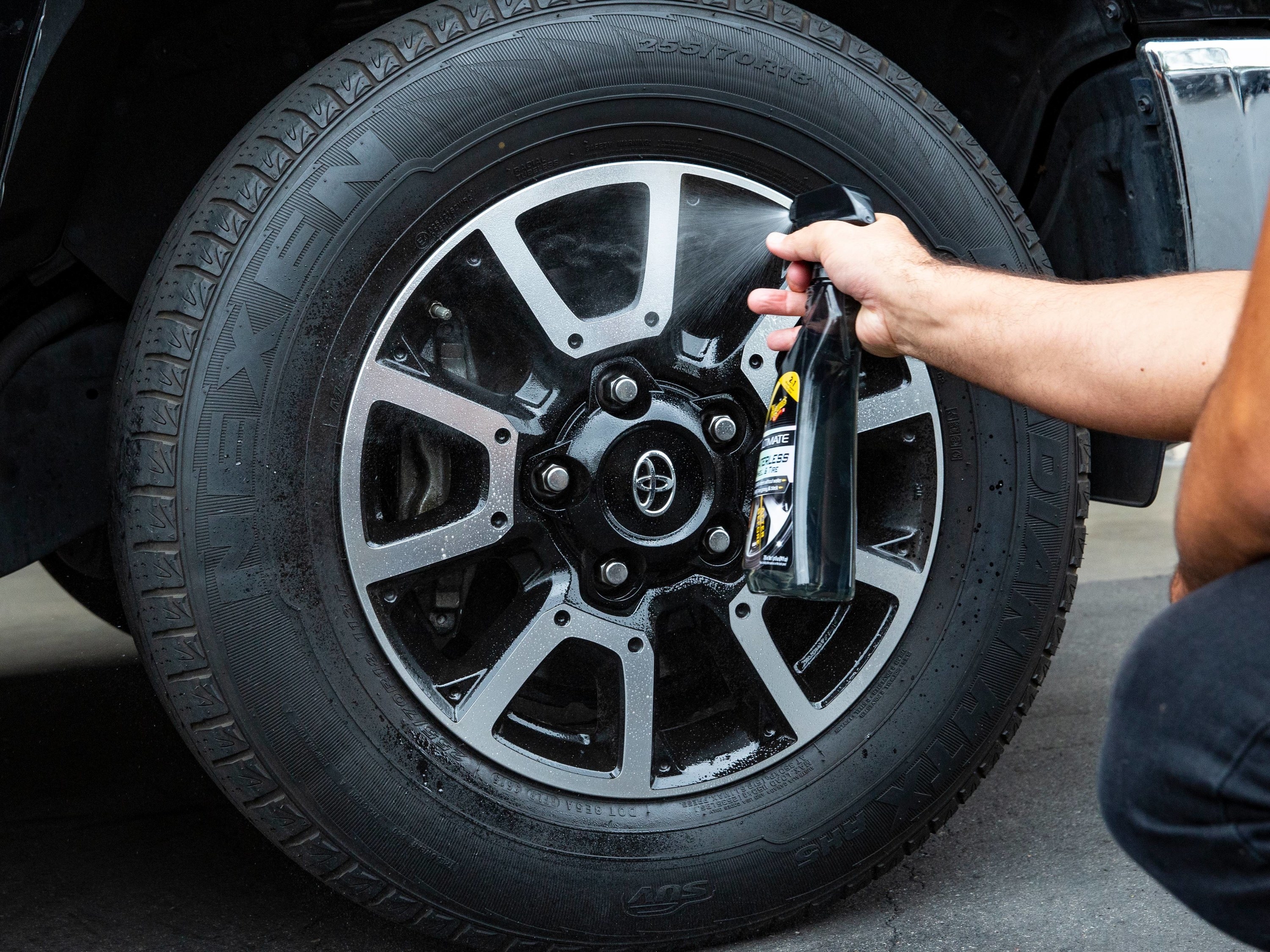 person spraying a wheel and tire dressing cleaner