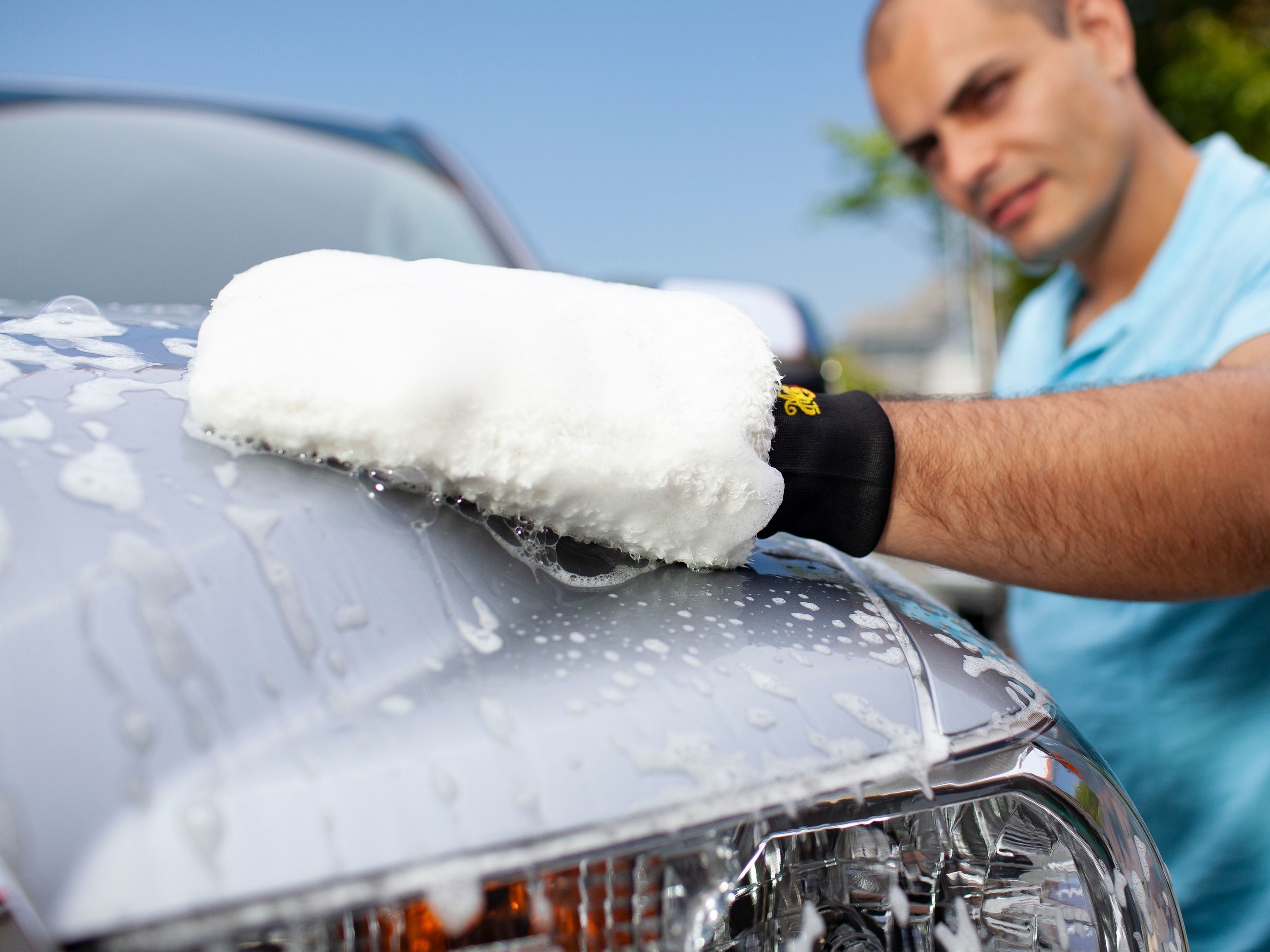 person using mitt to wash their car