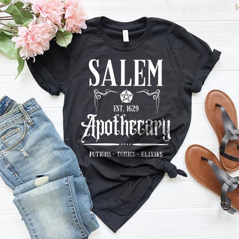 the salem apothecary t-shirt next to a pair of jeans and a pair of sandals