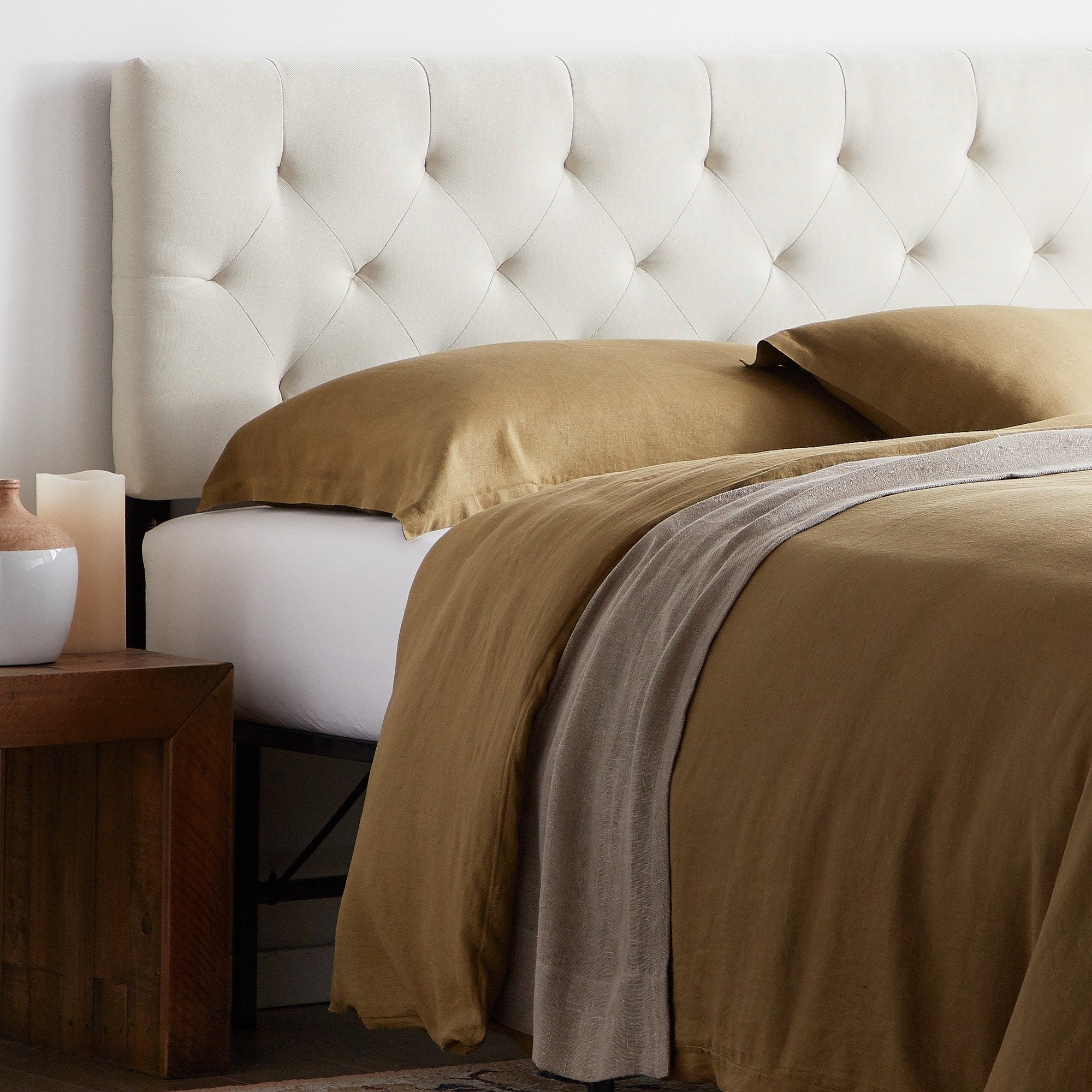 The cream tufted headboard behind a bed