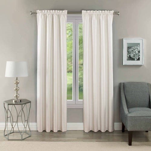 blackout curtains in the color white displayed on a window next to a chair and lamp