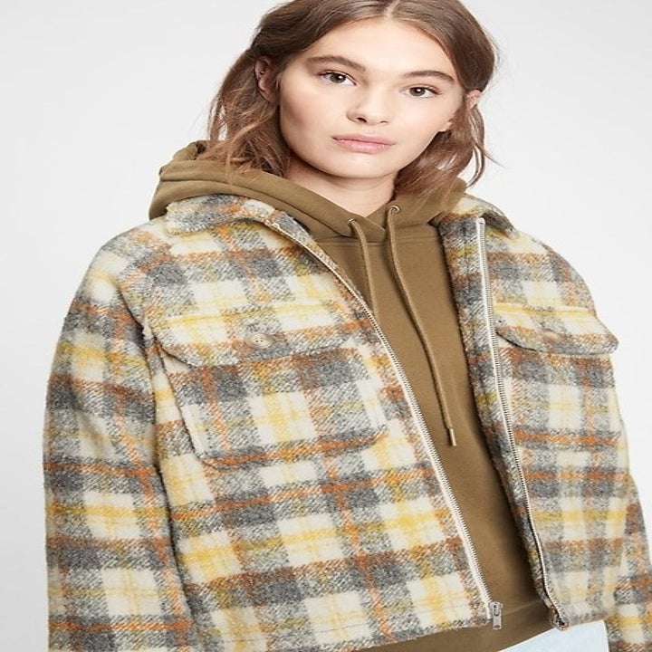 A model in a brown, blue, cream, and yellow plaid shirt jacket