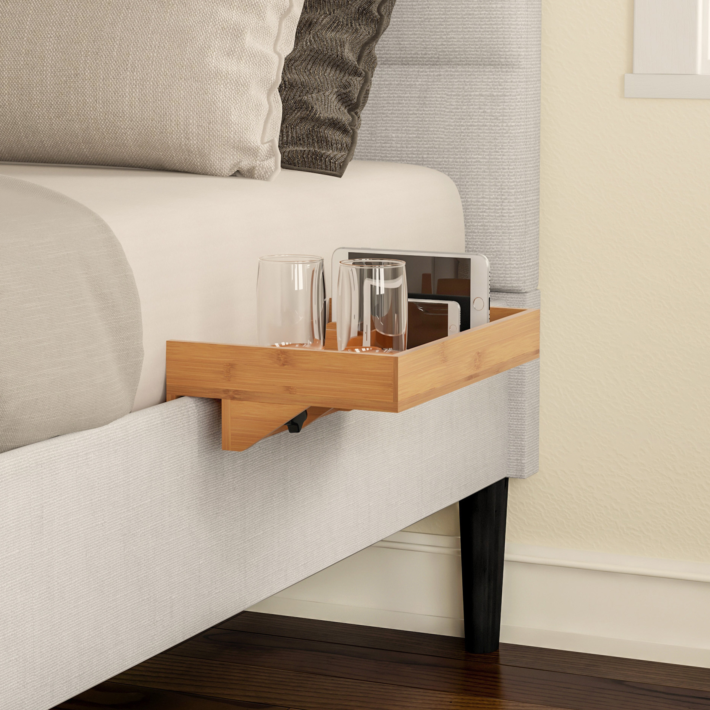 the bedside tray attached to a bed with a phone and glasses on top of it