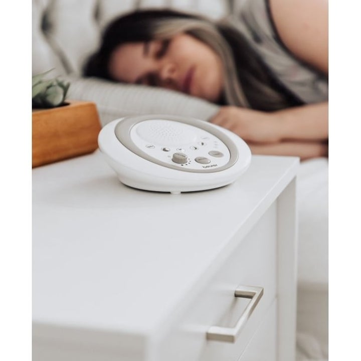 the sound machine next to a person sleeping in bed 
