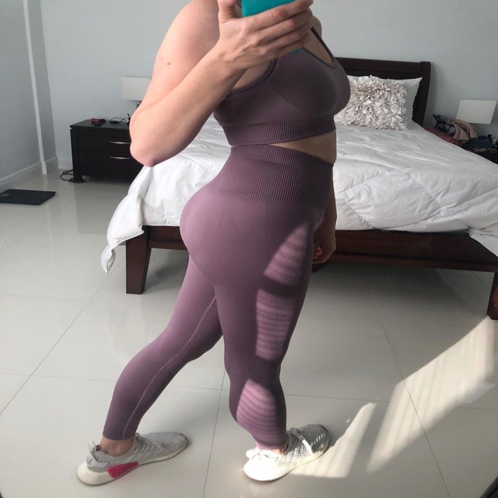 Reviewer wears plum-colored sports bra and leggings set