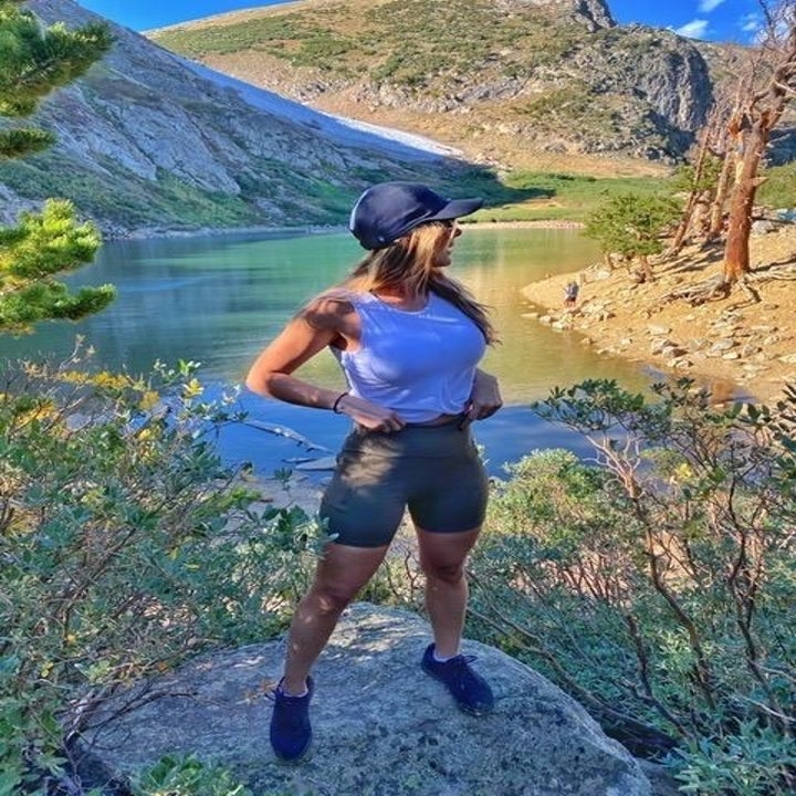 Reviewer wears same style workout crop top in a red shade with gray leggings