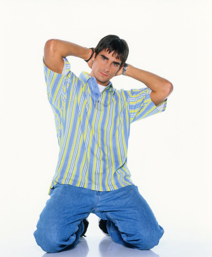 Kevin Richardson on his knees with his hands on his head posing seductively