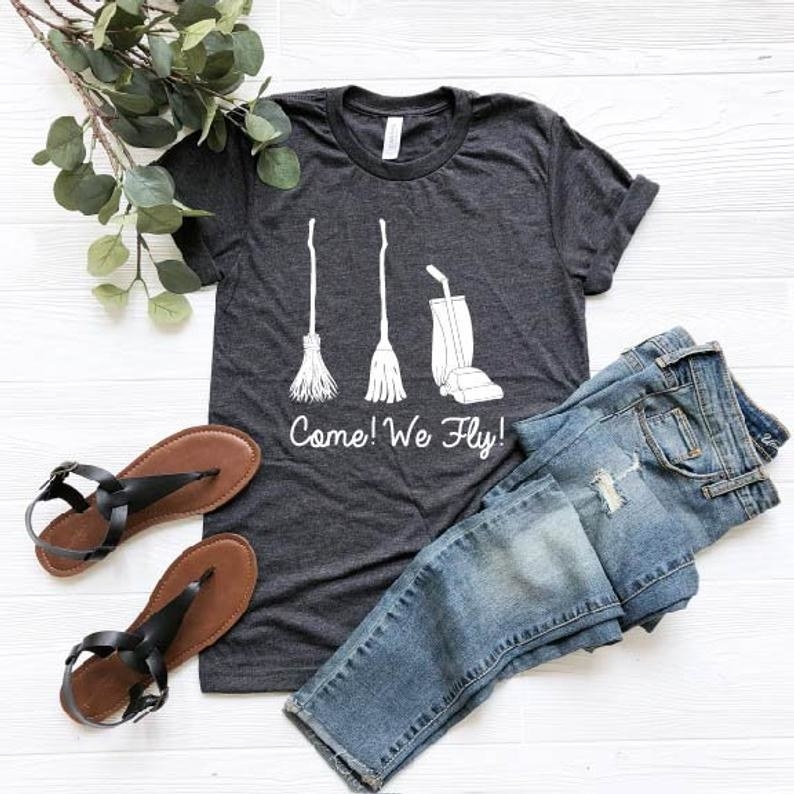 the come we fly shirt next to a pair of jeans and a pair of sandals