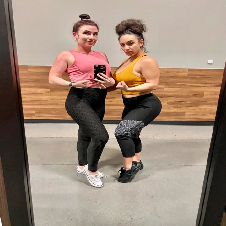 Reviewer wears pink twist-front crop top with black leggings at the gym