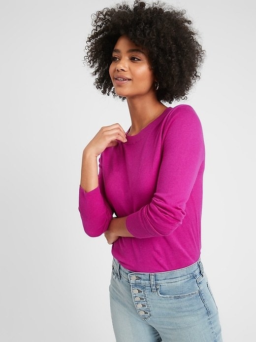 A model wearing the crew-neck sweater in blazing sunset which looks like magenta