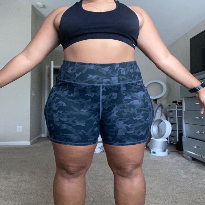 Reviewer wears same style bike shorts in a swirly dark blue print with a black sports bra