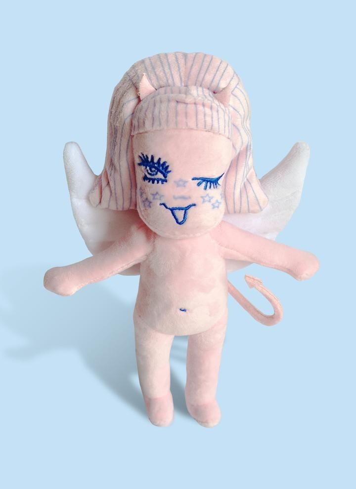 a pink angel plushie with wings, a tail, and little horns 