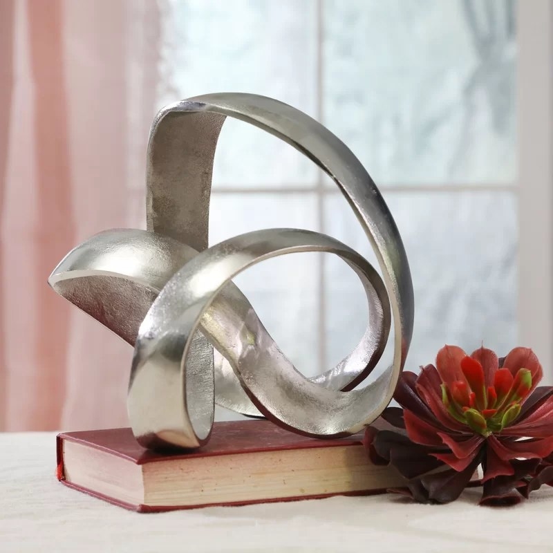 The silver sculpture resting on top of a book