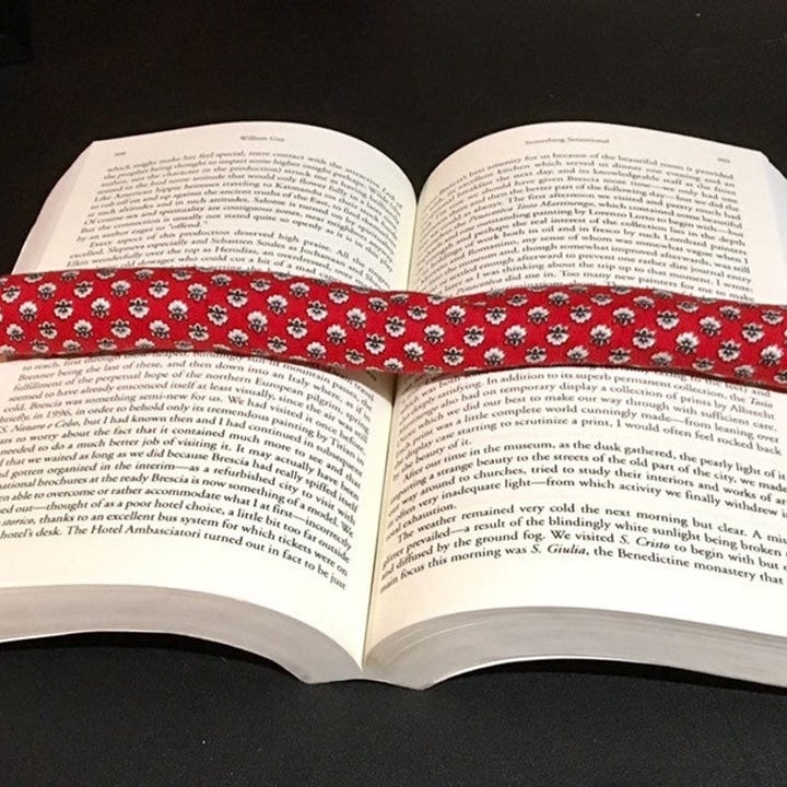 Red book weight with white floral design on it being used to hold open a book