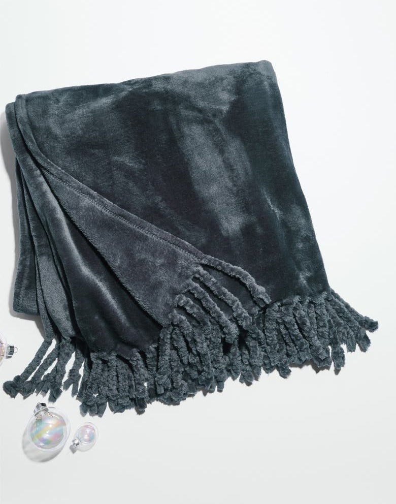 The velvet blanket in blue with fringe on the ends