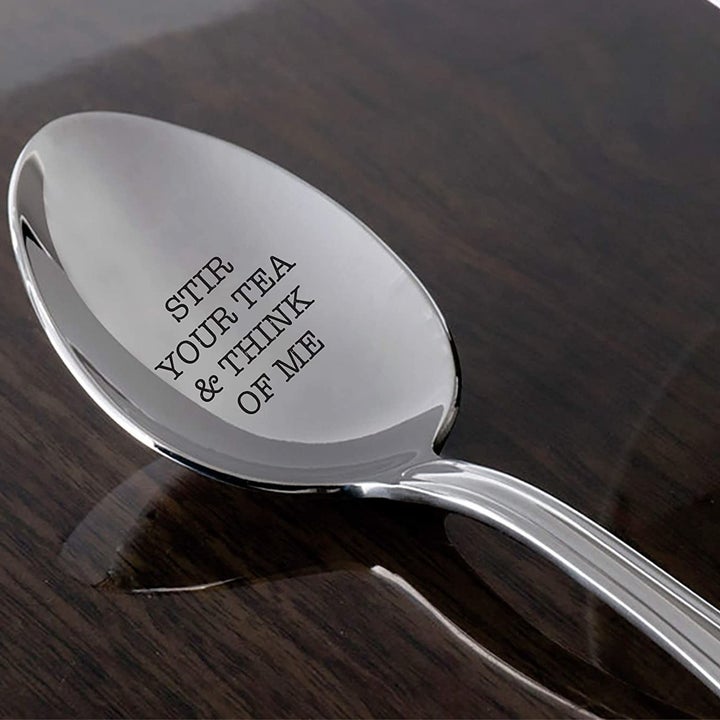 A silver spoon engraved with "Stir your tea and think of me"
