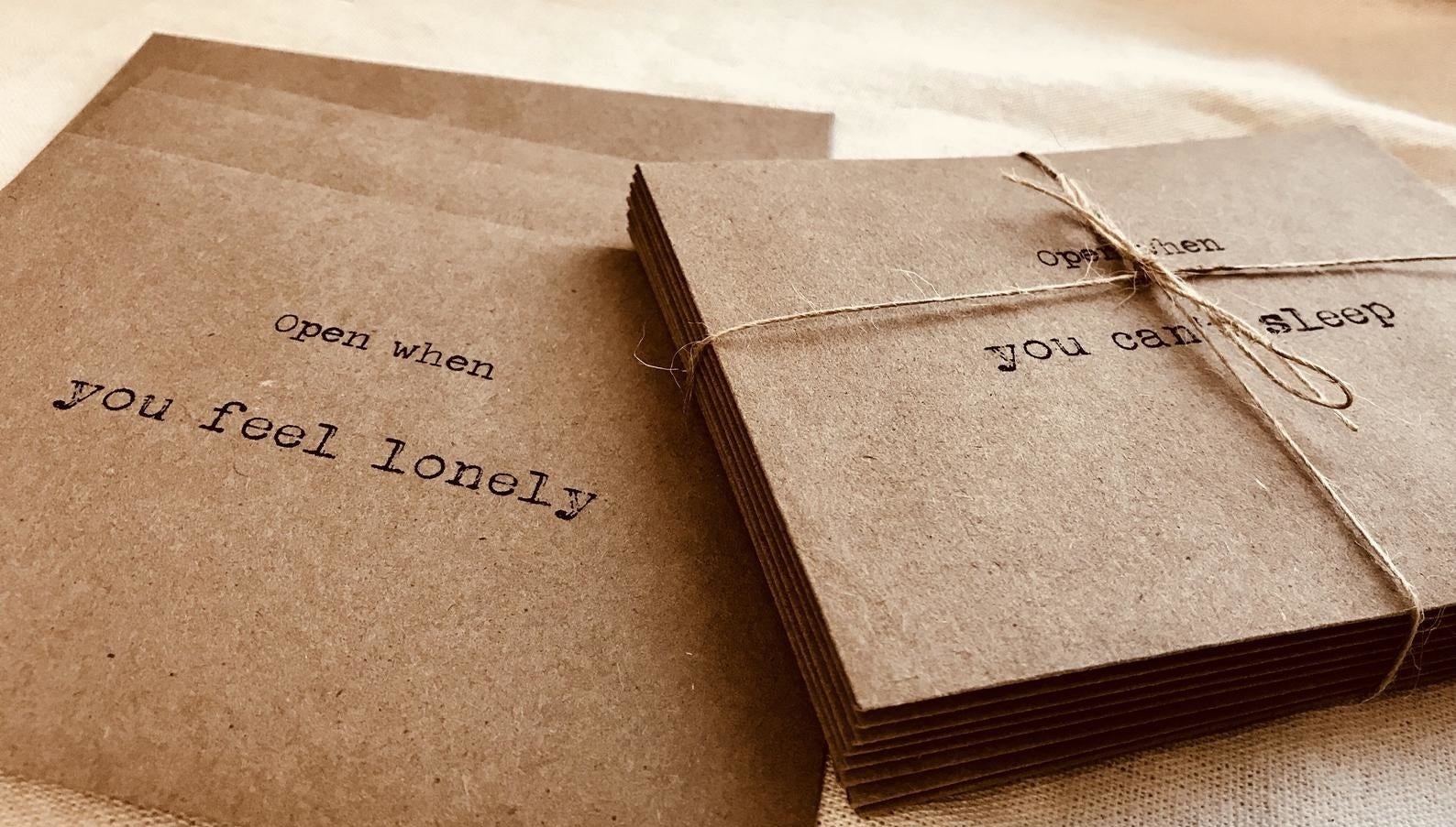 Two stacks of brown envelopes stamped with &quot;Open when you feel lonely&quot; and &quot;open when you can&#x27;t sleep&quot; 