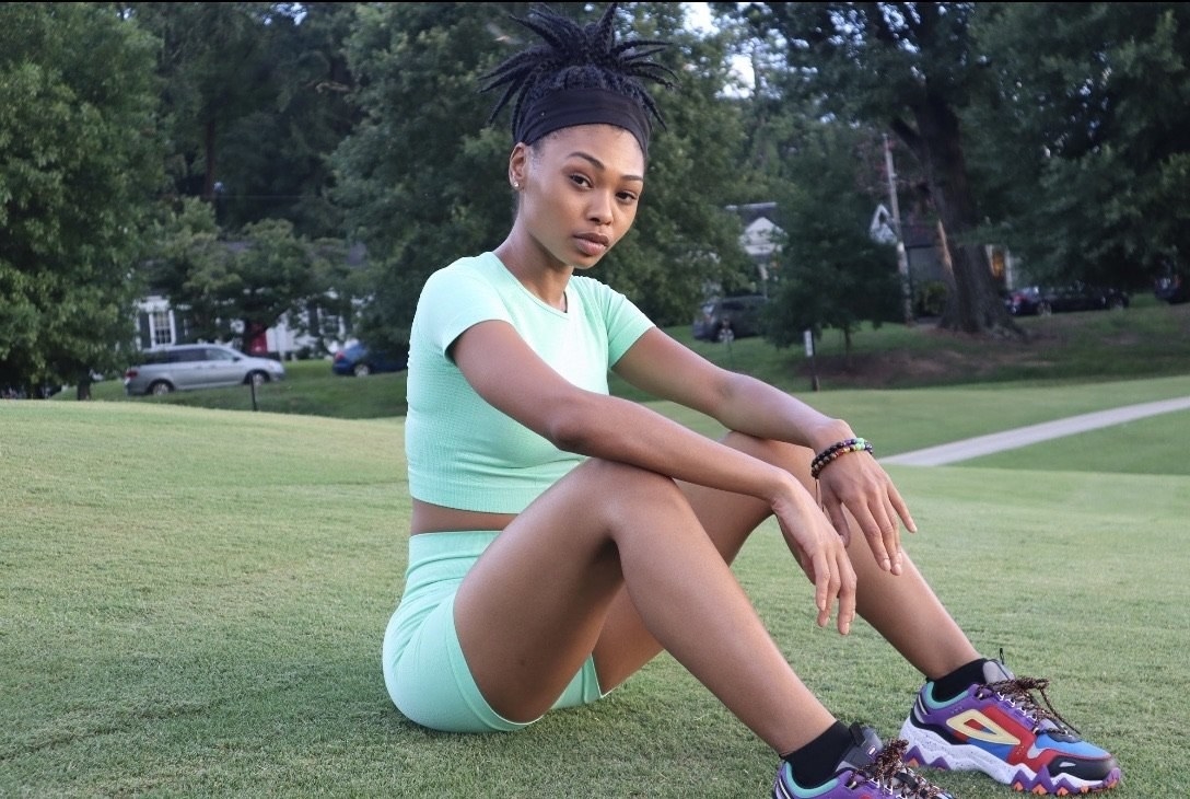 Model wears light. green crop top with matching shorts and colorful athletic sneakers