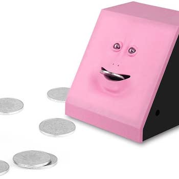 The pink piggybank with its mouth open and a coin inserted
