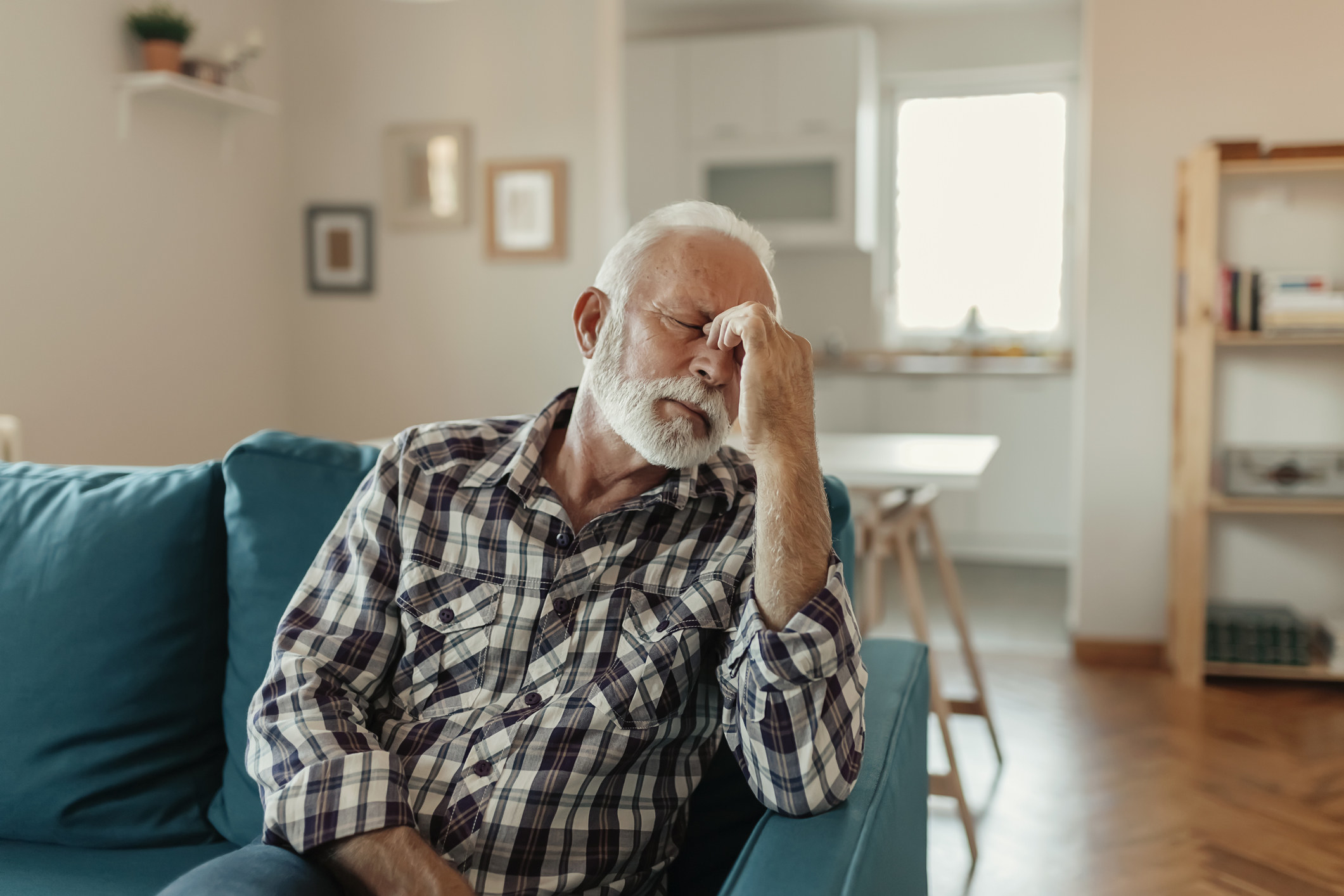 Older man looking unwell on blue couch.