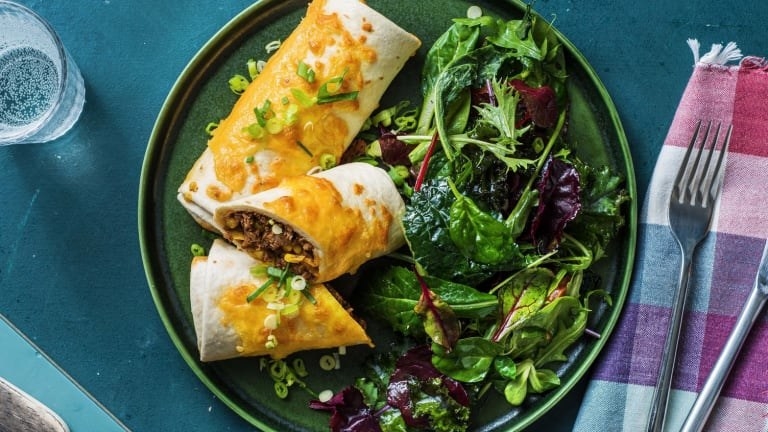 The beef and corn chimichanga covered in queso with a side salad