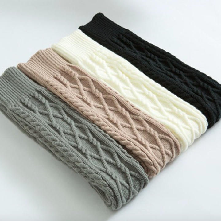 A set of four neatly folded cable knit socks on a simple background