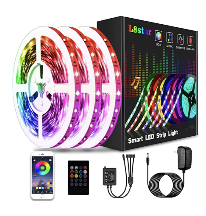 A rope of multicolored lights next to a box, romote control, a cell phone, and wires to show its use
