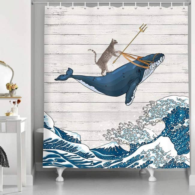 The shower curtain with an illustration of a cat riding a whale and holding a trident