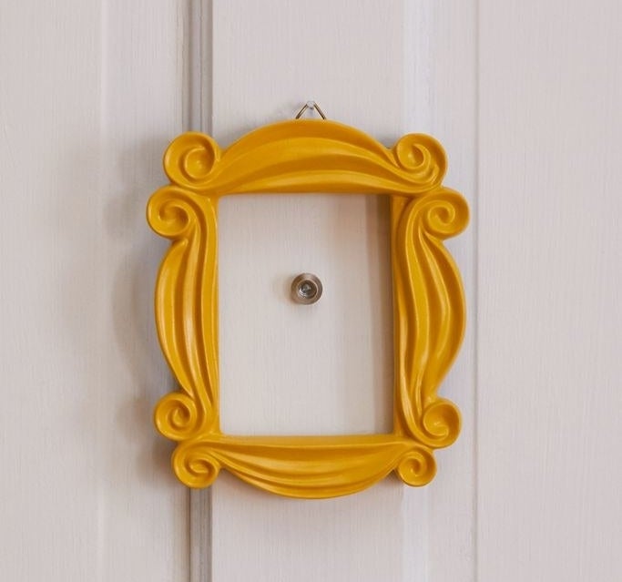 The yellow picture frame hung around a door's peephole