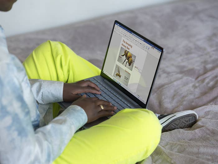 A person making a presentation on their computer while sitting crosslegged on their bed