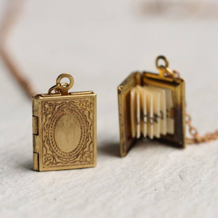The gold tone pocket that looks like an antique book from the front and pictured with the locket open to show the pleated paper message