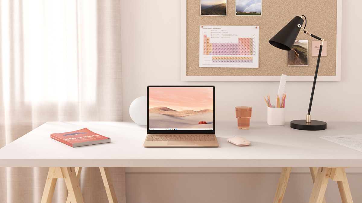 The Microsoft laptop on a desk next to stationery supplies and a lamp