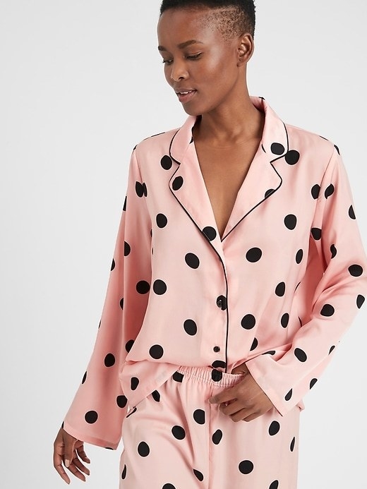 A model wearing the pajama top in pink with black dots