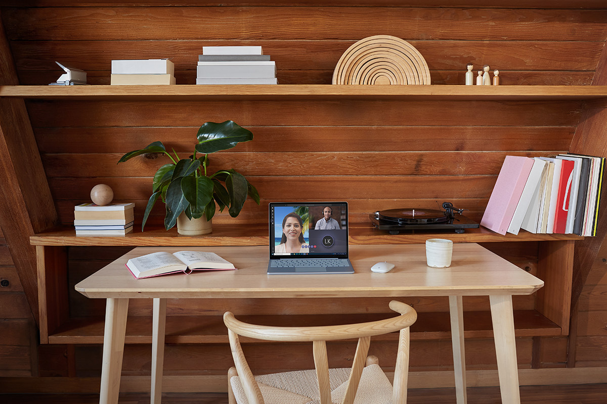 The laptop on a wooden desk with a video chat on the screen