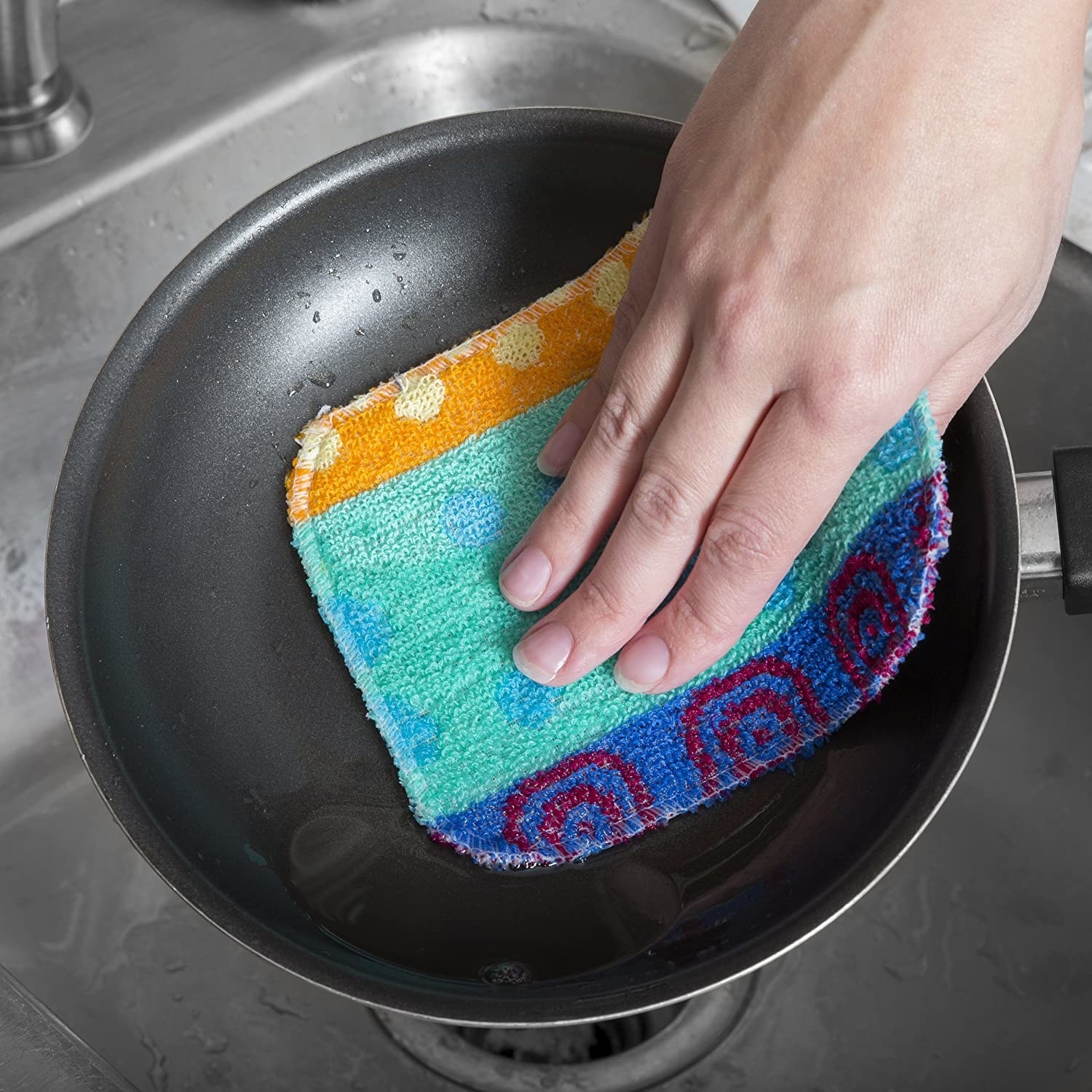 A person scrubbing a pan with the cloth