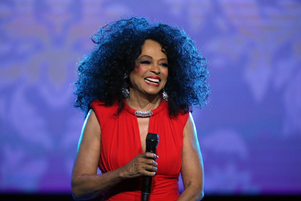 Diana Ross performing at an event in 2019 or 2020, holding a microphone and smiling