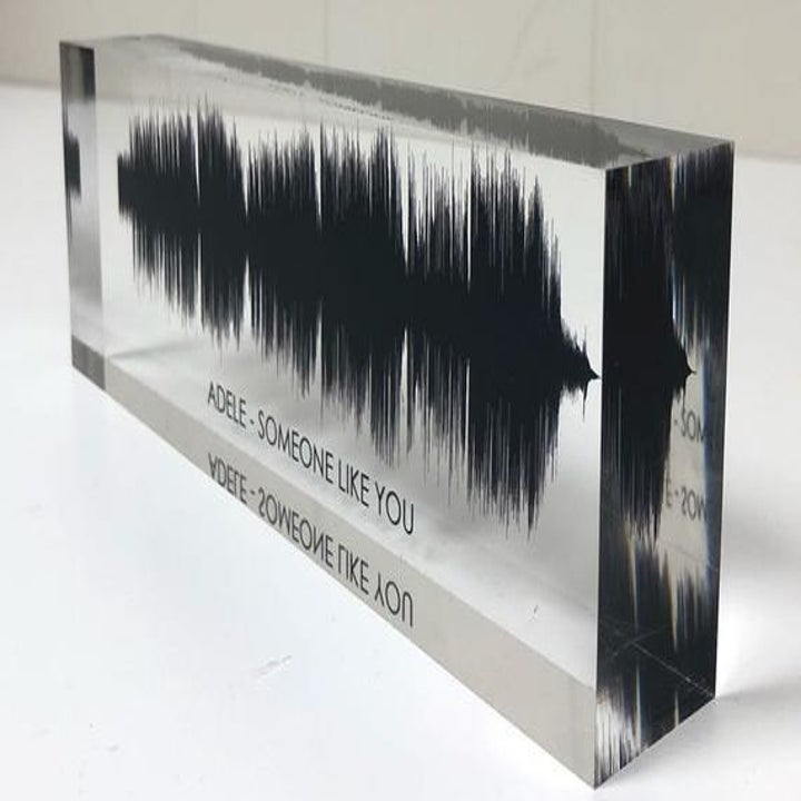 A slim glass block printed with a black soundwave and text that reads "Adele - Someone Like You" 