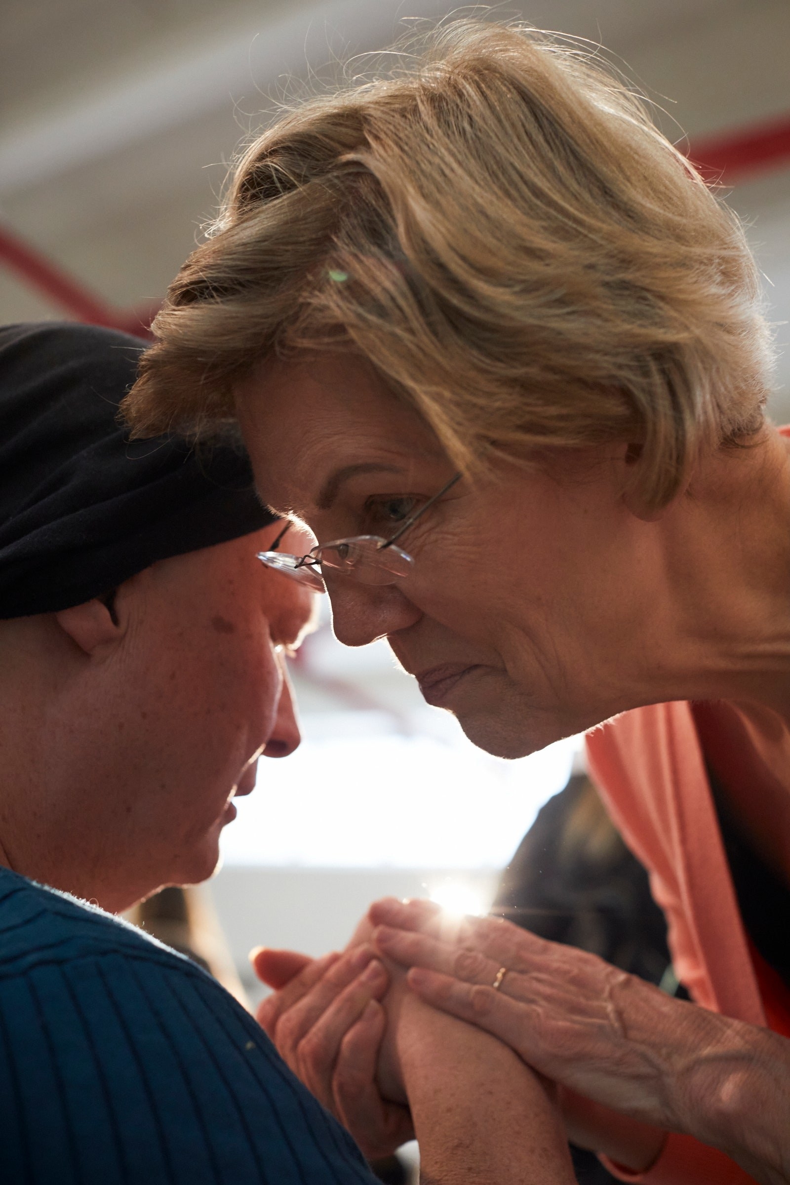 Former presidential candidate Elizabeth Warren leaning over to speak to someone, facing slightly away from the camera