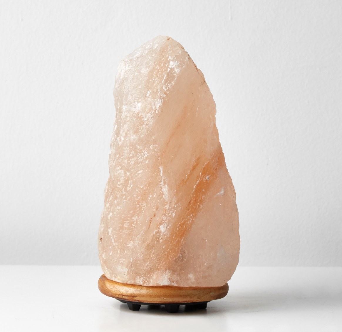 The Himalayan salt crystal lamp in blush pink with a wood stand