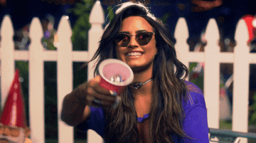 GIF of Demi throwing confetti out of a cup