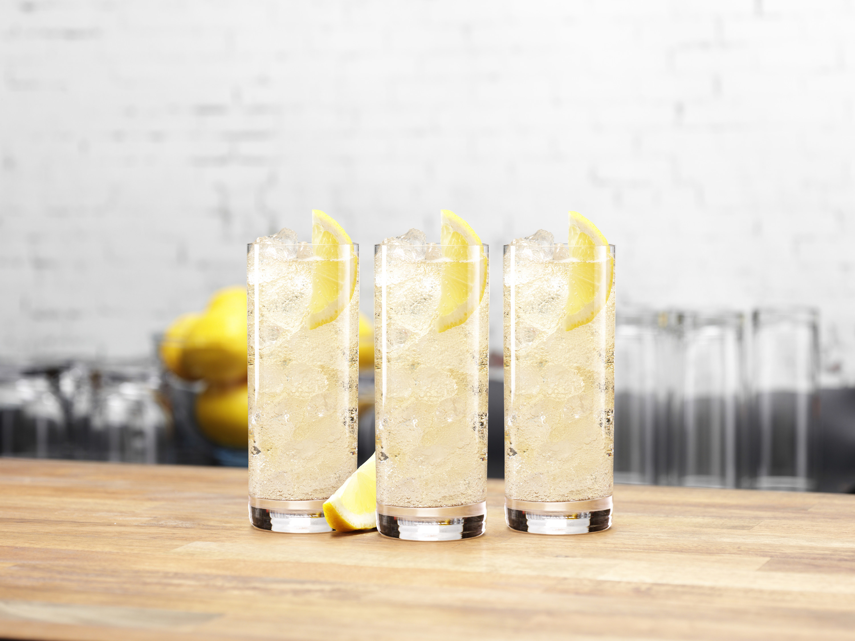 Three highball glasses filled with ice and liquid all garnished with a slice of lemon 