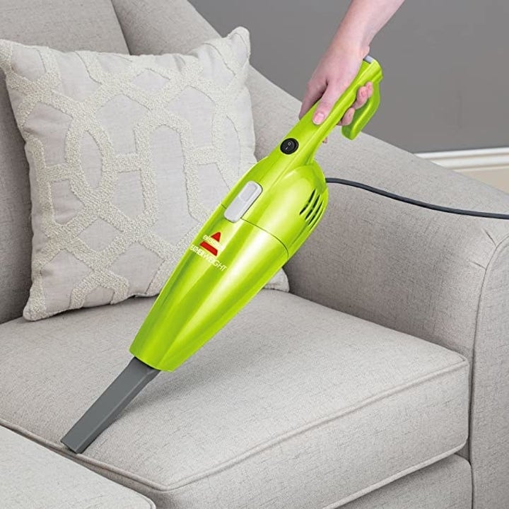 The vacuum being used to clean a sofa
