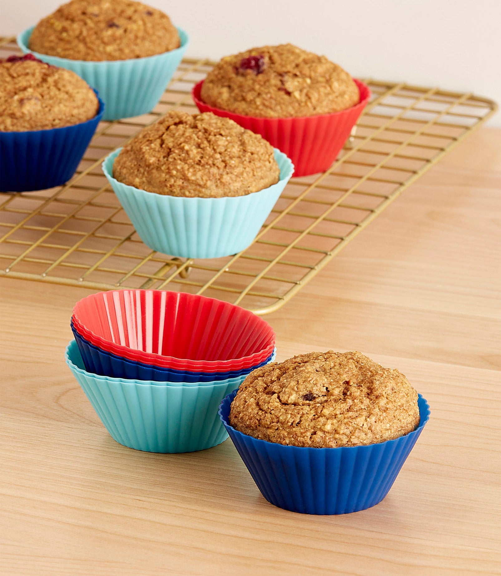A batch of muffins in silicone baking cups cooling on a wire rack