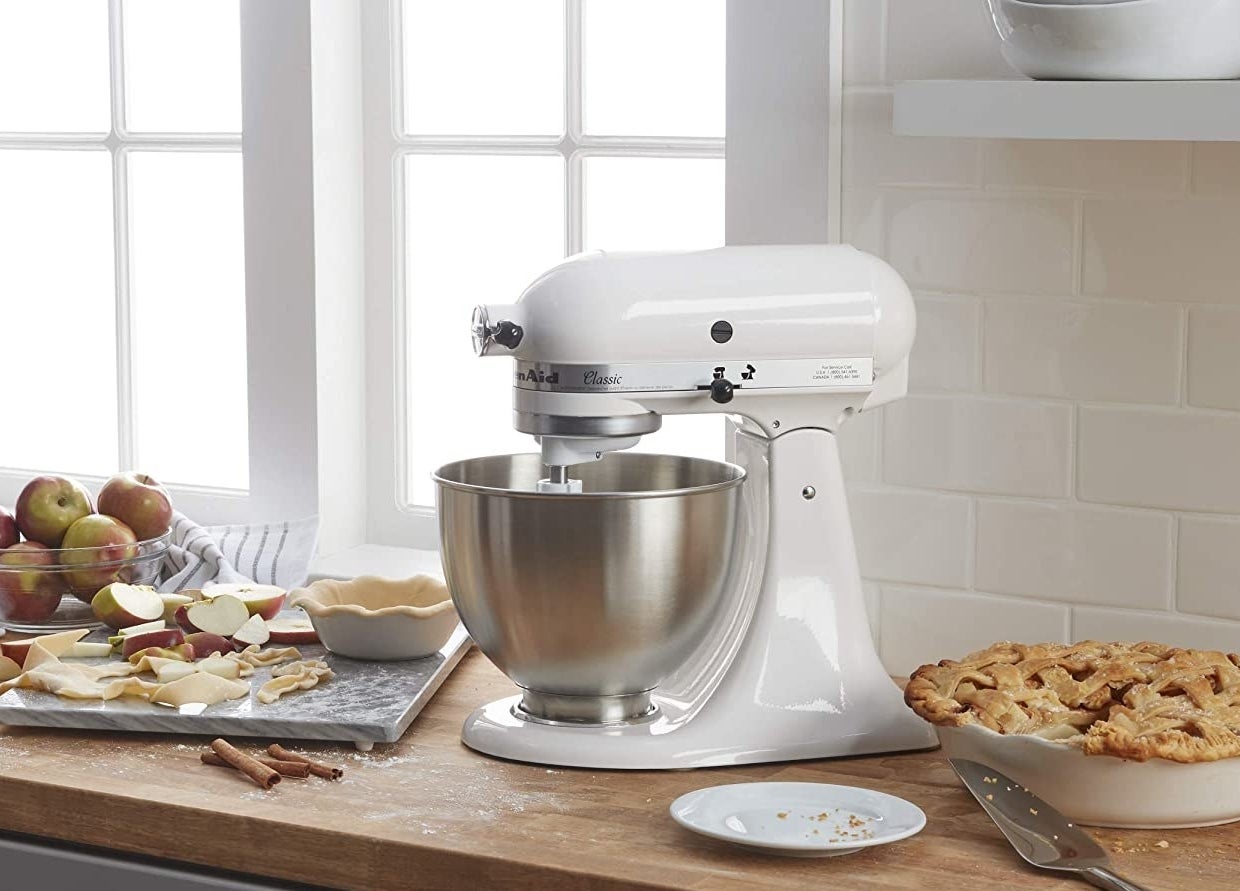 A large stand mixer on a counter top with a baked pie next to it