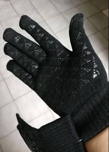 Reviewer in black gloves showing rubber grooves on inside of the hand for gripping and touch screens 