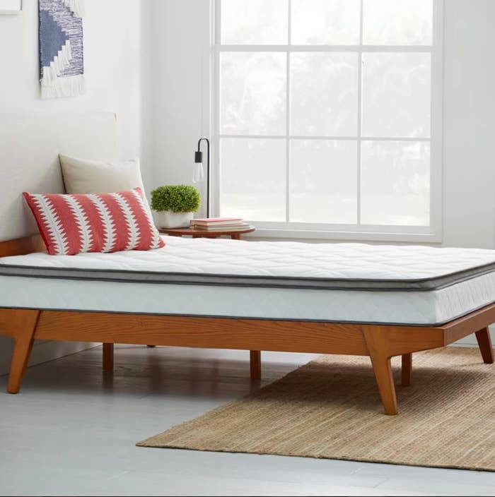 The medium-firm mattress in queen white on top of a wood bedframe