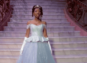 Brandy as Cinderella walking down a staircase in her ball gown and tiara